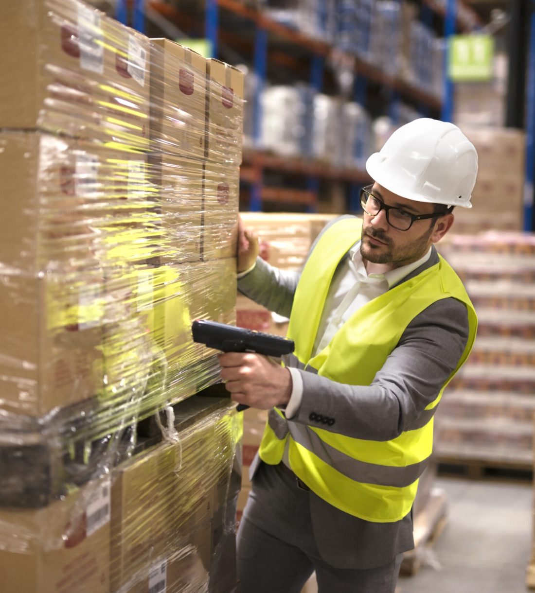 Male warehouse worker using bar code scanner to analyze newly arrived goods for further placement in storage department.